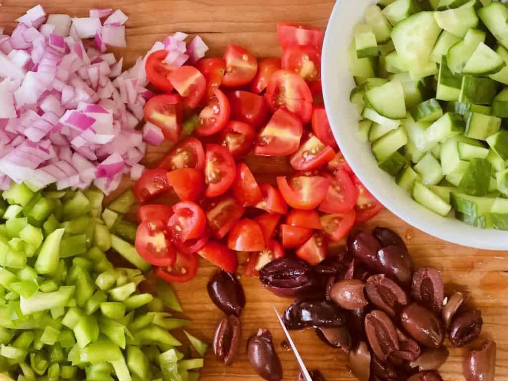 Diced vegetables for Vegan Greek Salad on a cutting board