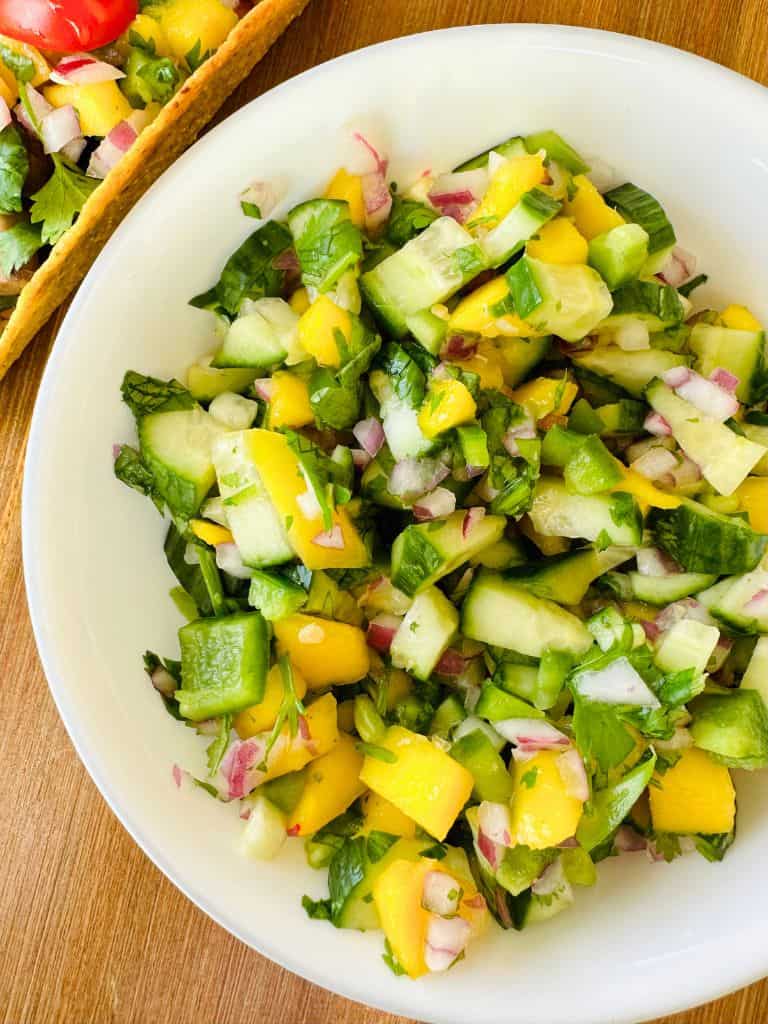 mango cucumber salsa in a bowl with a taco on the side