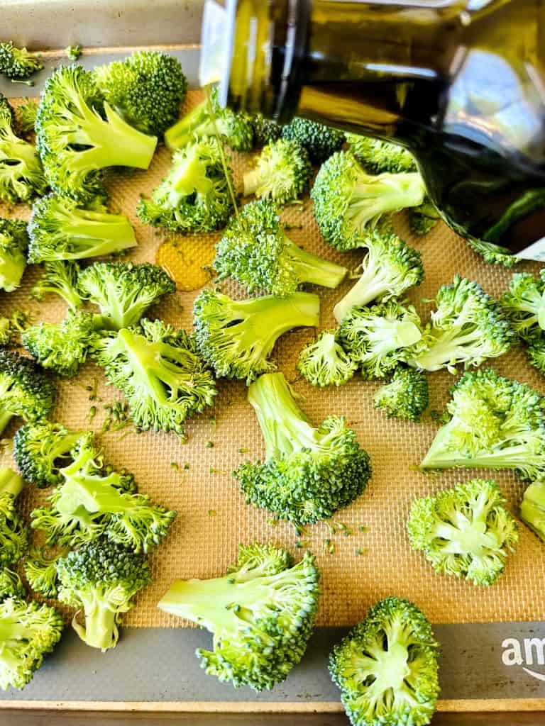 olive oil pouring over broccoli to make roasted broccoli