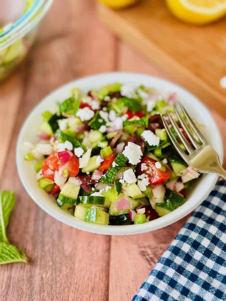 Vegan Greek salad in a white bowl with a fork
