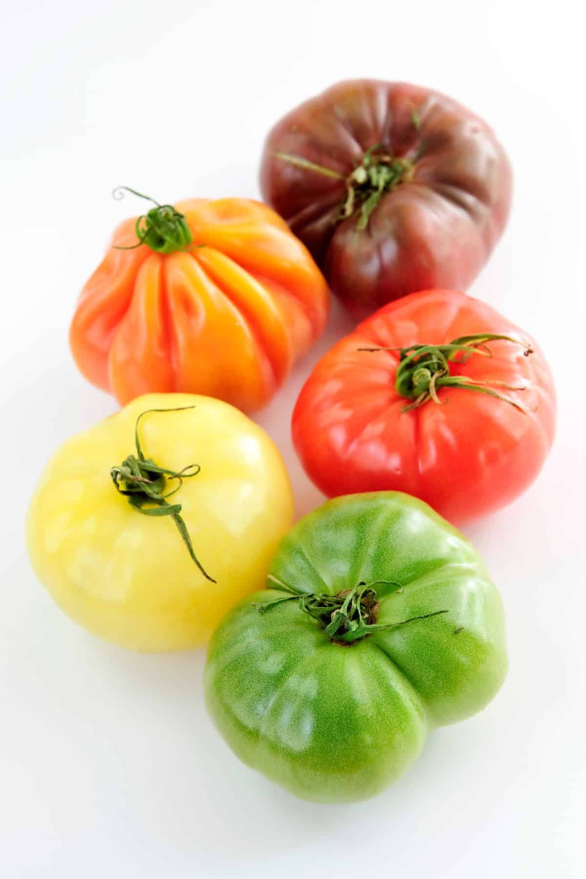 five multi colored Heirloom Tomatoes on a white background