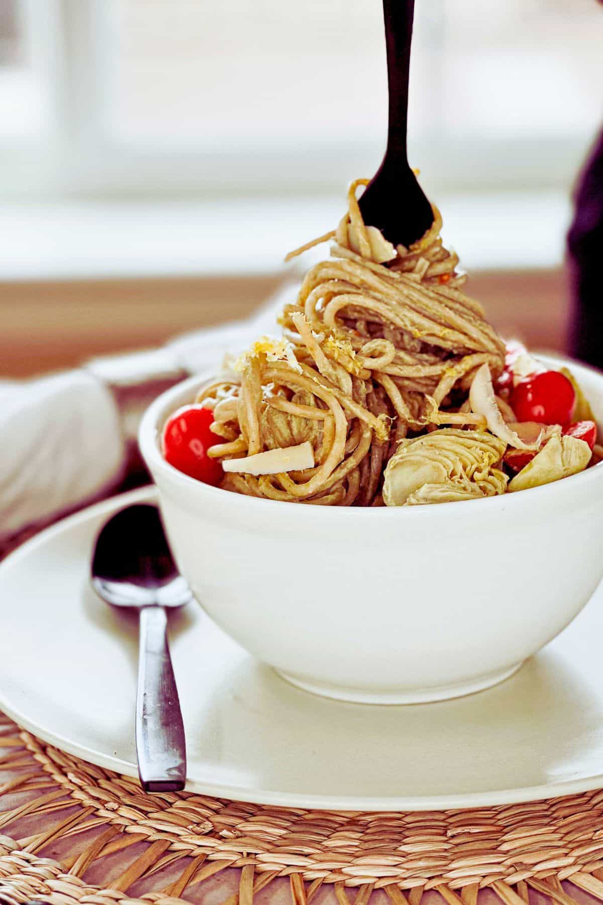 side view of bowl of pasta with a fork twirling some pasta.