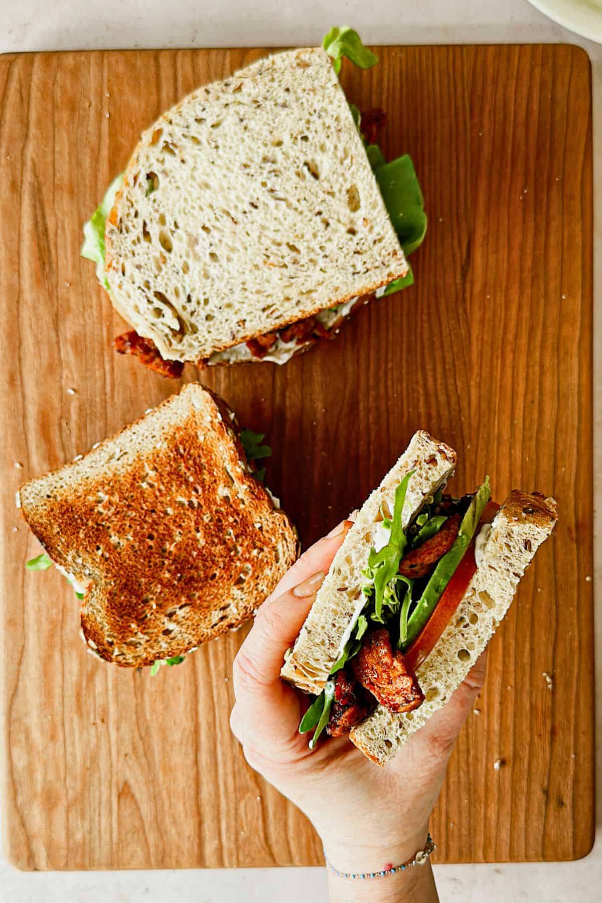 hand holding Vegan BLT sandwich