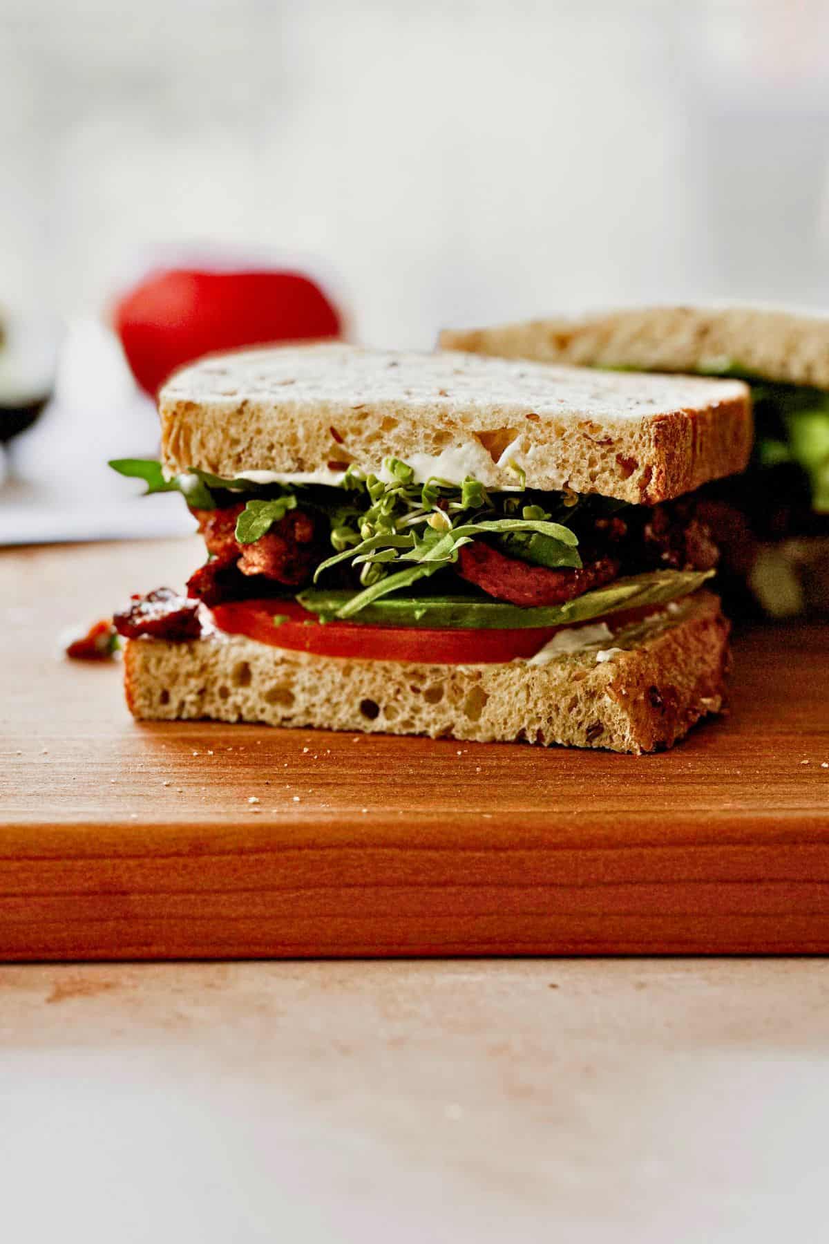 side view of Vegan BLT sandwich with soy curls on a cutting board