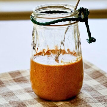 close up side view of a clear jar with sauce inside.