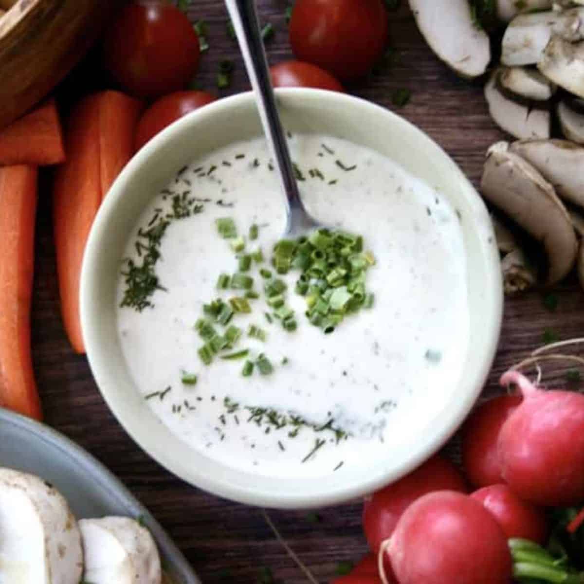 vegan ranch dressing in a bowl surrounded by vegetables