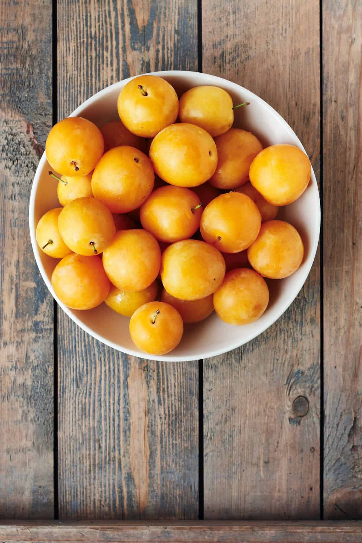 Yellow plums in a bowl top view
