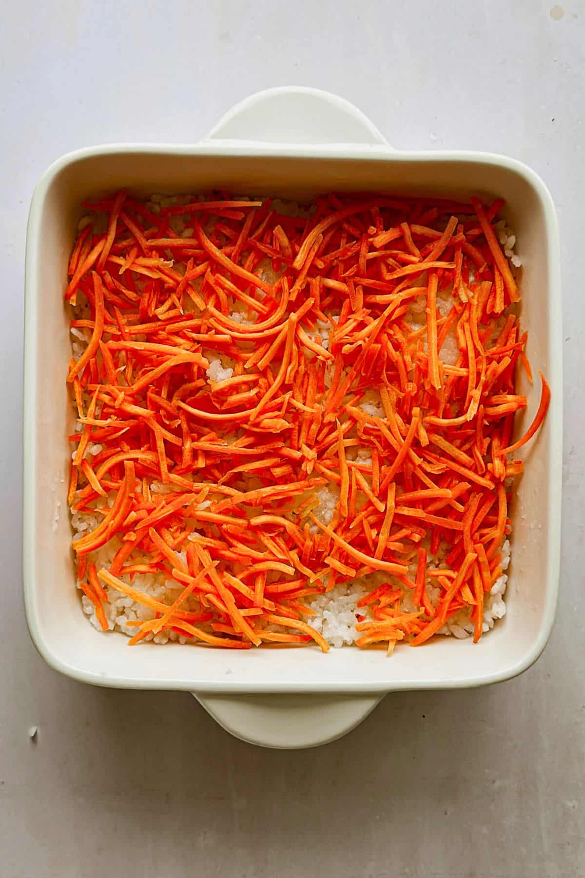 adding a layer of carrots to the layer of rice top view