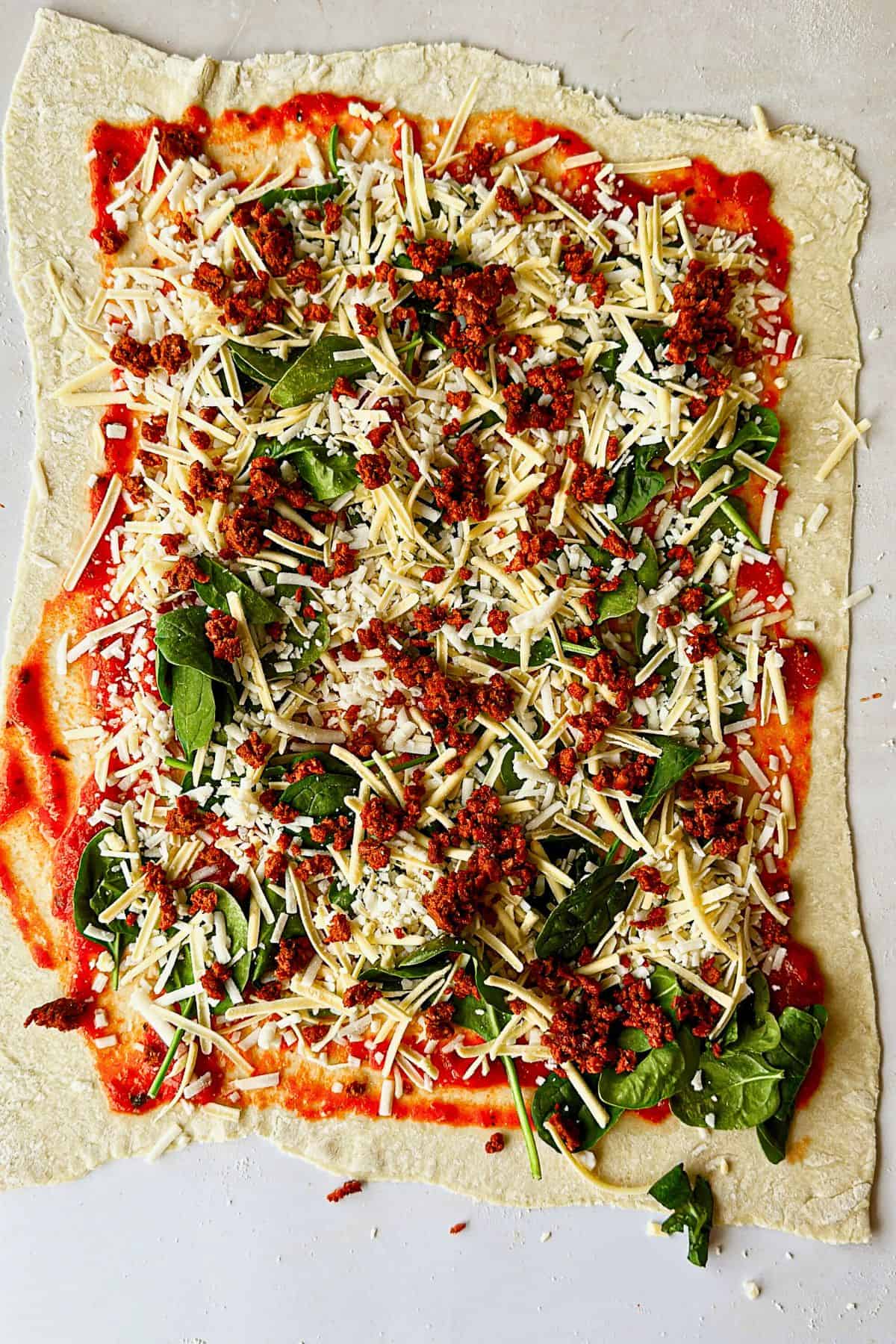 adding chorizo to dough for vegan pizza rolls; top view