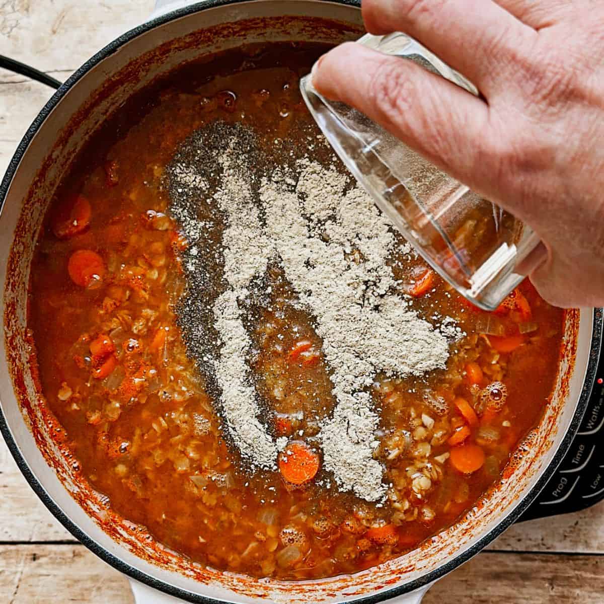 adding salt and pepper to healthy vegan red lentil soup