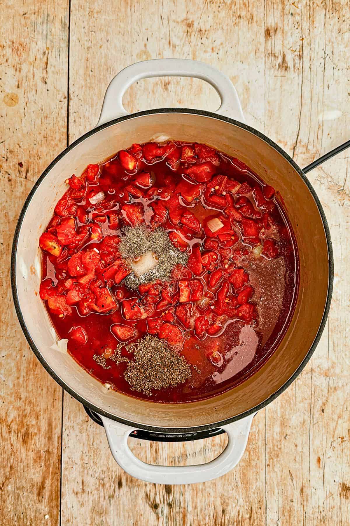 adding seasonings to vegan tomato soup