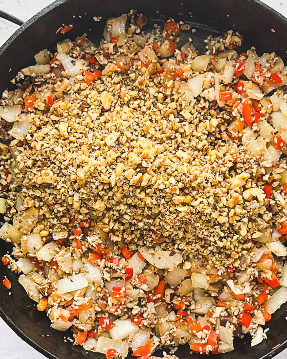 Step 5: adding walnuts to vegan picadillo mixture in a pan