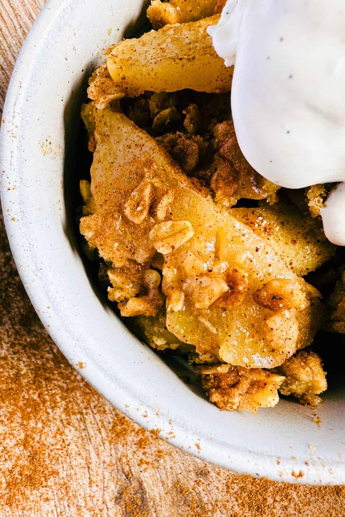 apple crisp vegan in a bowl topped with ice cream close up