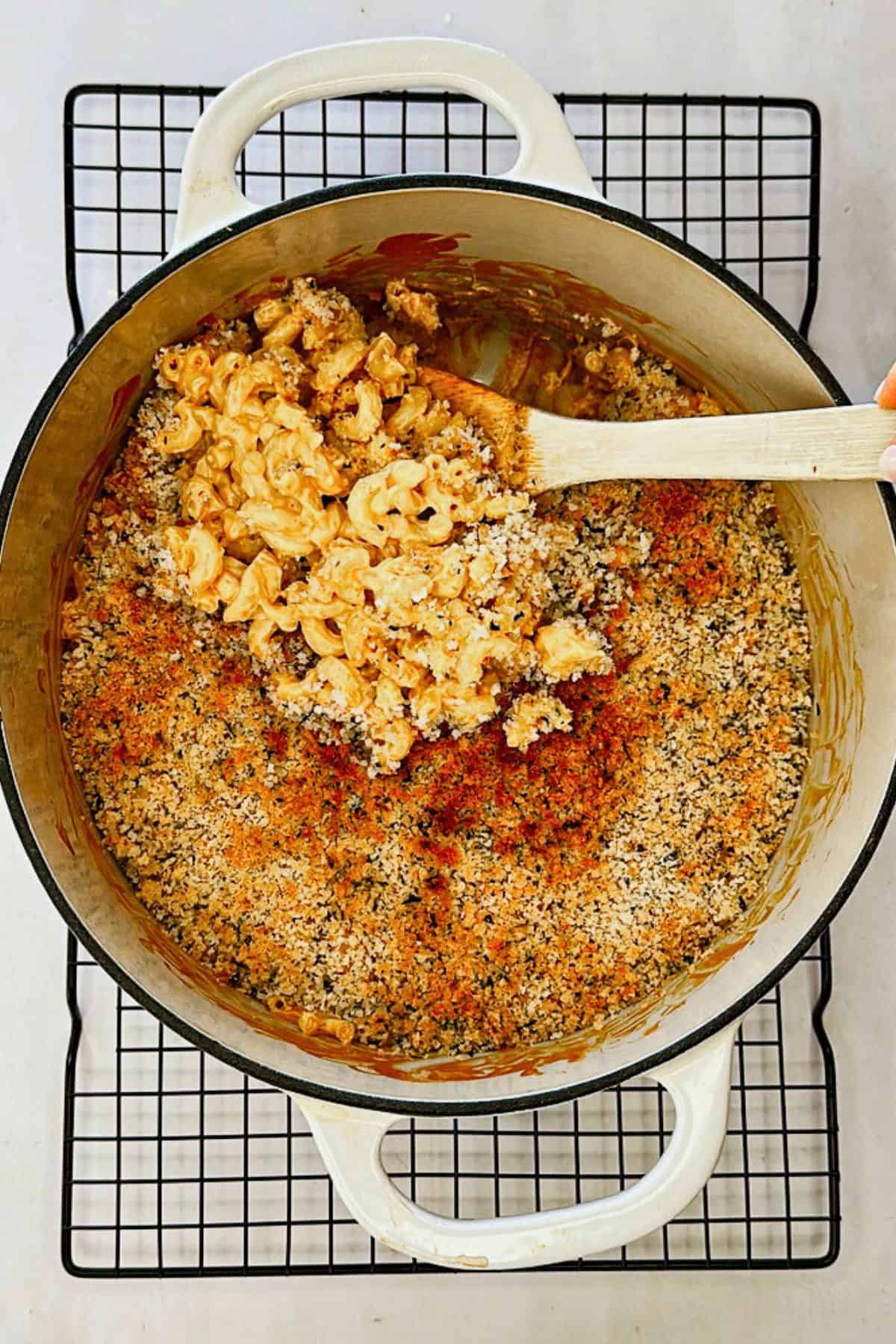 scooping out baked vegan mac and cheese with breadcrumb topping