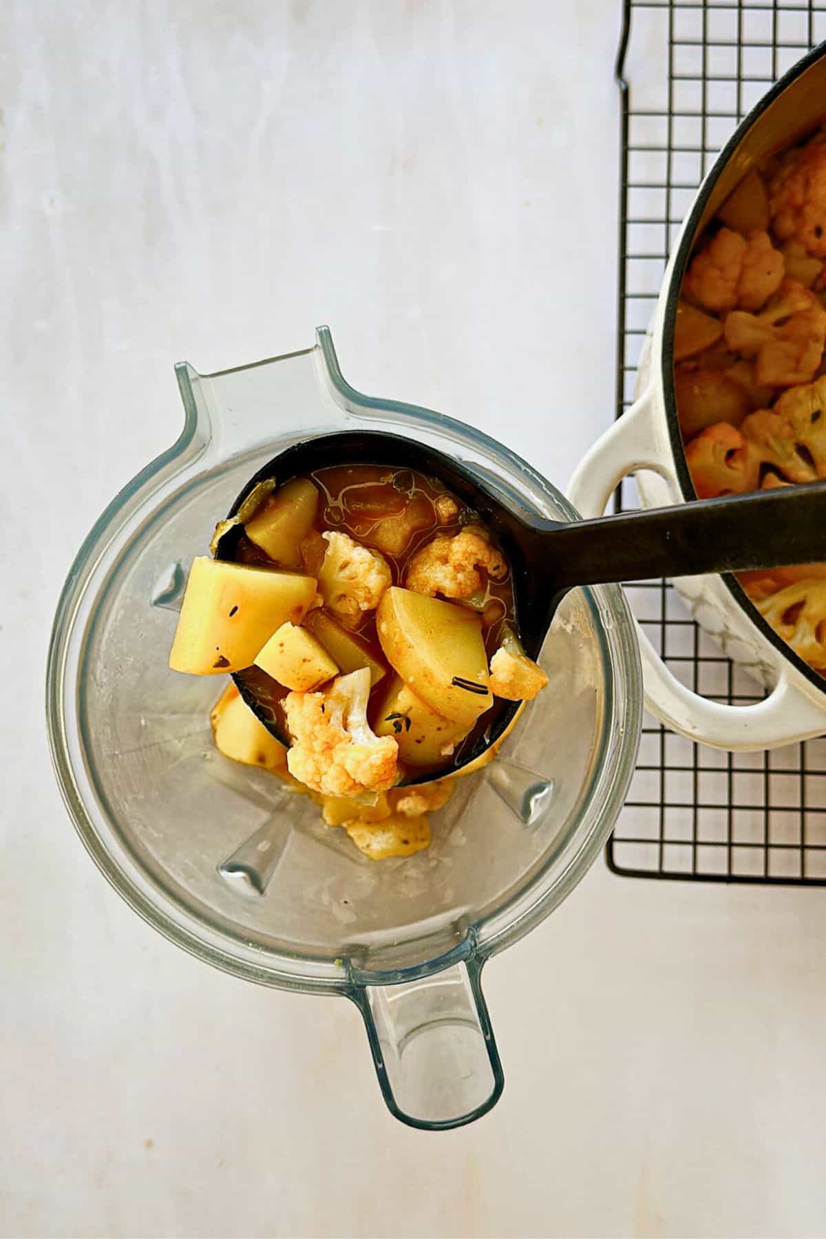 pouring vegan potato and cauliflower soup into a blender to puree