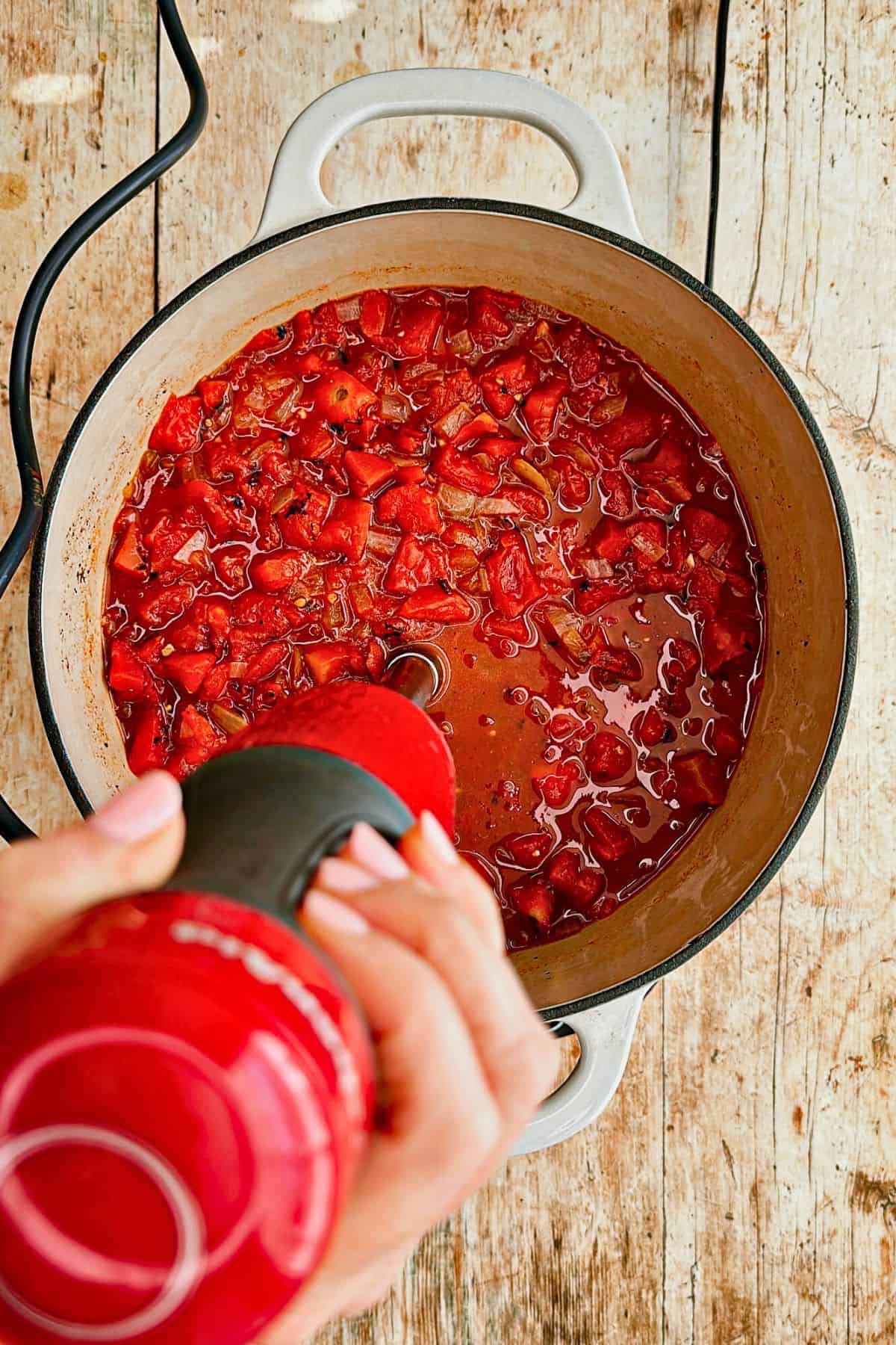 blending vegan tomato soup with immersion blender