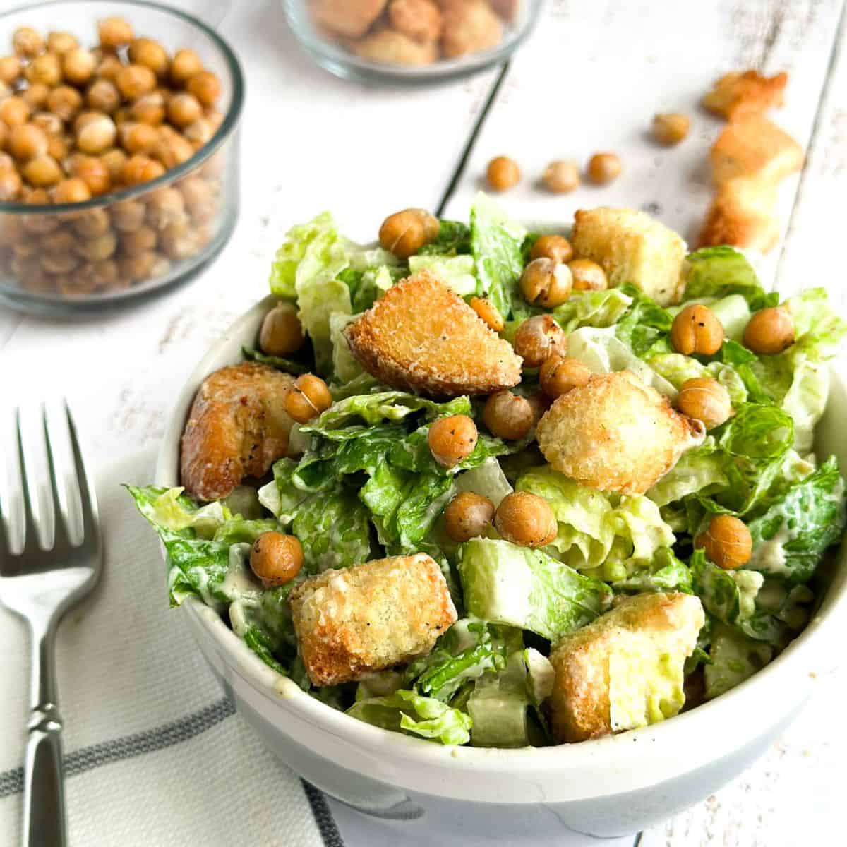 vegan caesar salad in a bowl, side view, topped with homemade croutons and roasted chickpeas