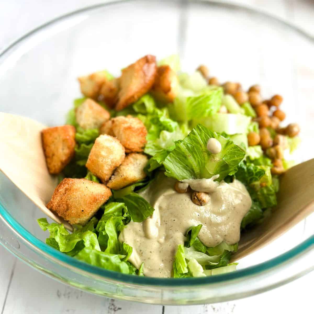 preparing a vegan caesar salad in a serving bowl, side view