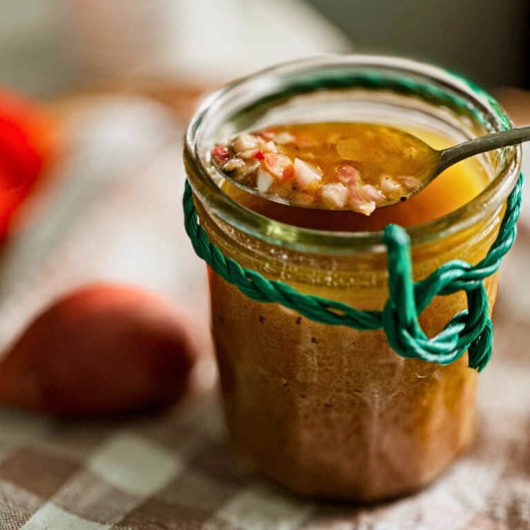 classic French dressing in a jar with a spoon picking up some dressing