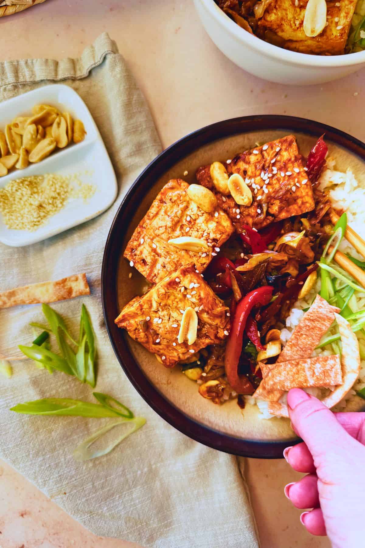 hand grabbing a crispy egg wrapper strip on vegan egg roll bowl