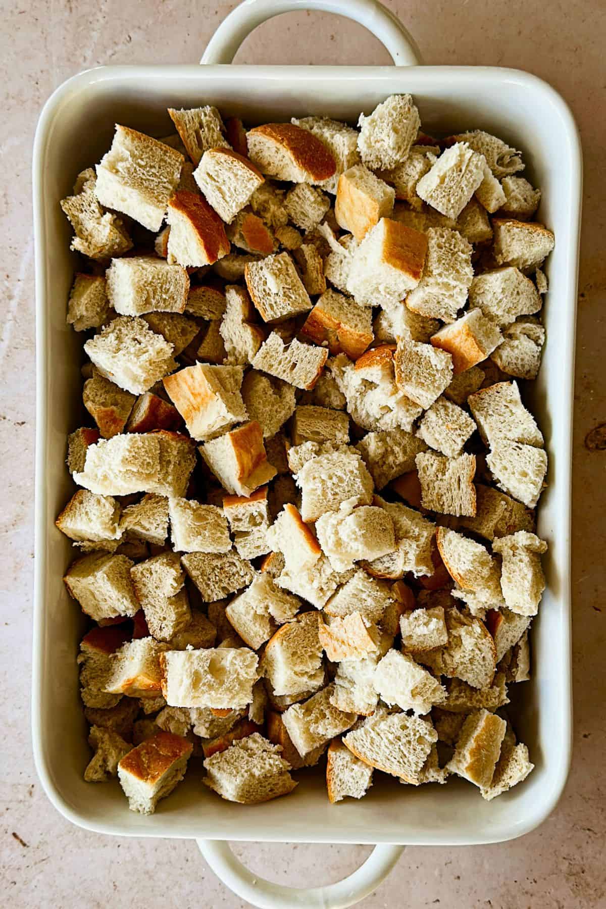 top view of chopped cubed bread in a white casserole dish.