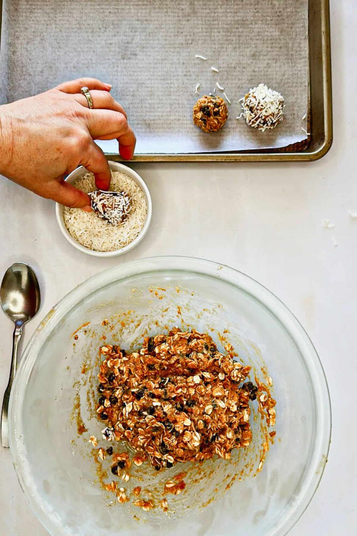 dipping vegan chocolate chip energy balls in a coconut shreds