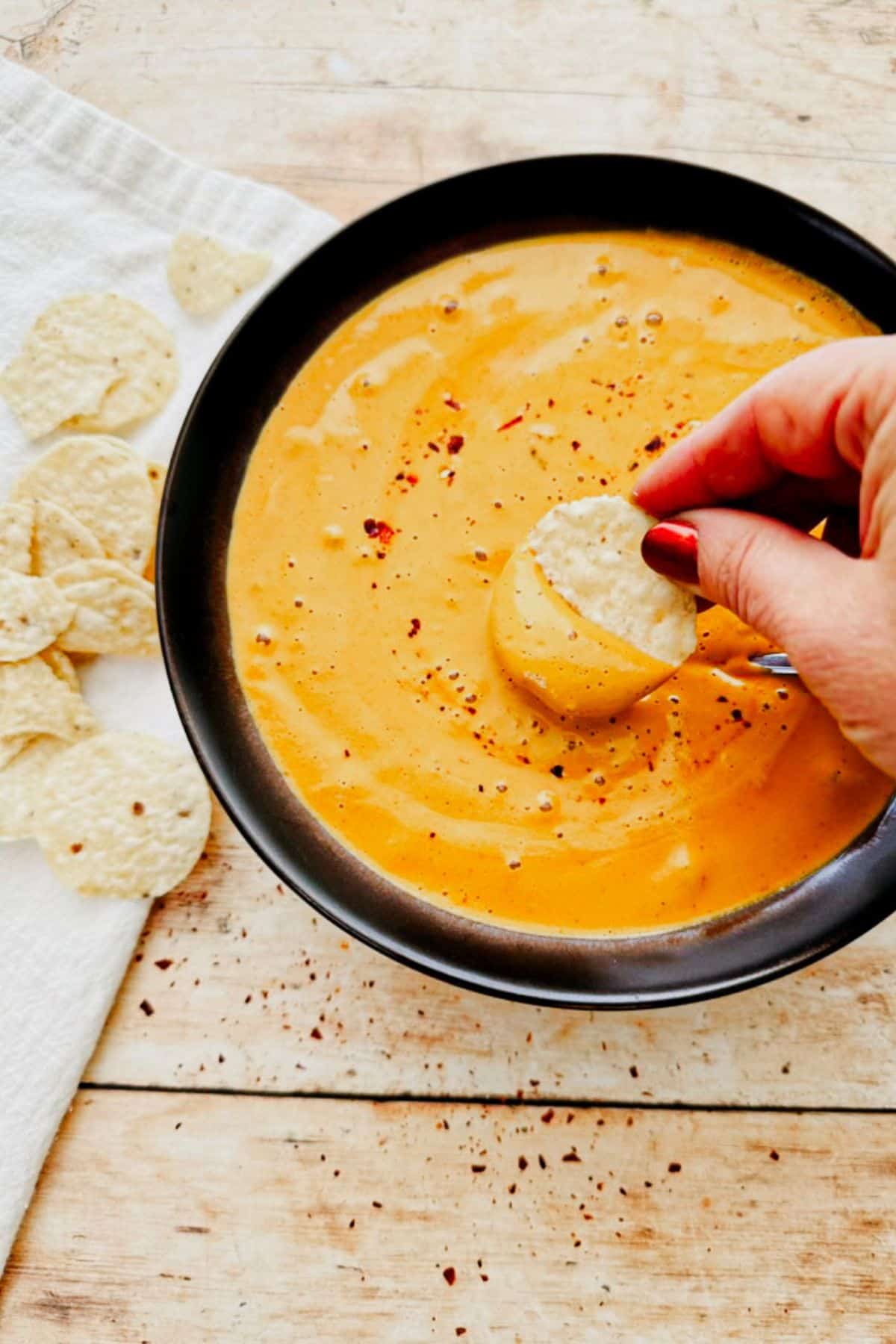 a chip picking up easy vegan cashew queso in a bowl