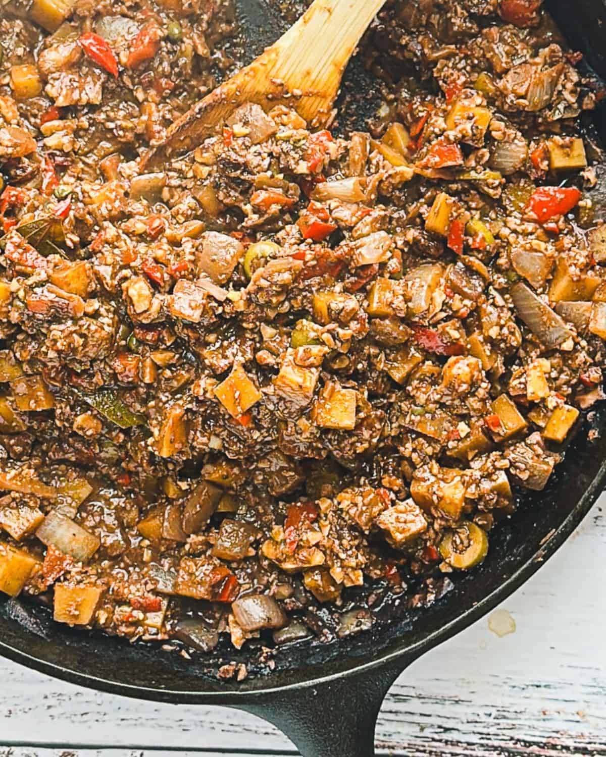 Step 7: finished vegan picadillo in pan with a wooden spoon stirring the mixture.