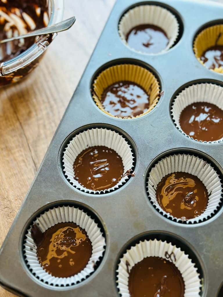 first layer of chocolate in paper cupcake wrappers in a cupcake tray