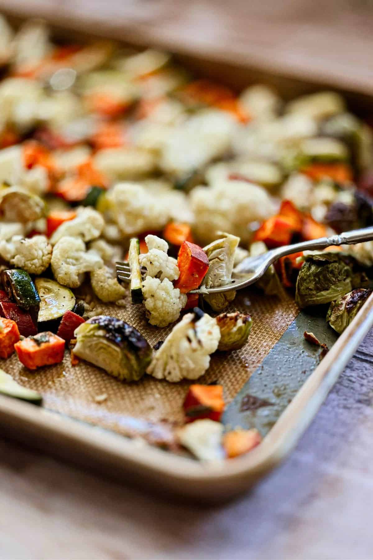 fork lifting roasted vegetables from a pan