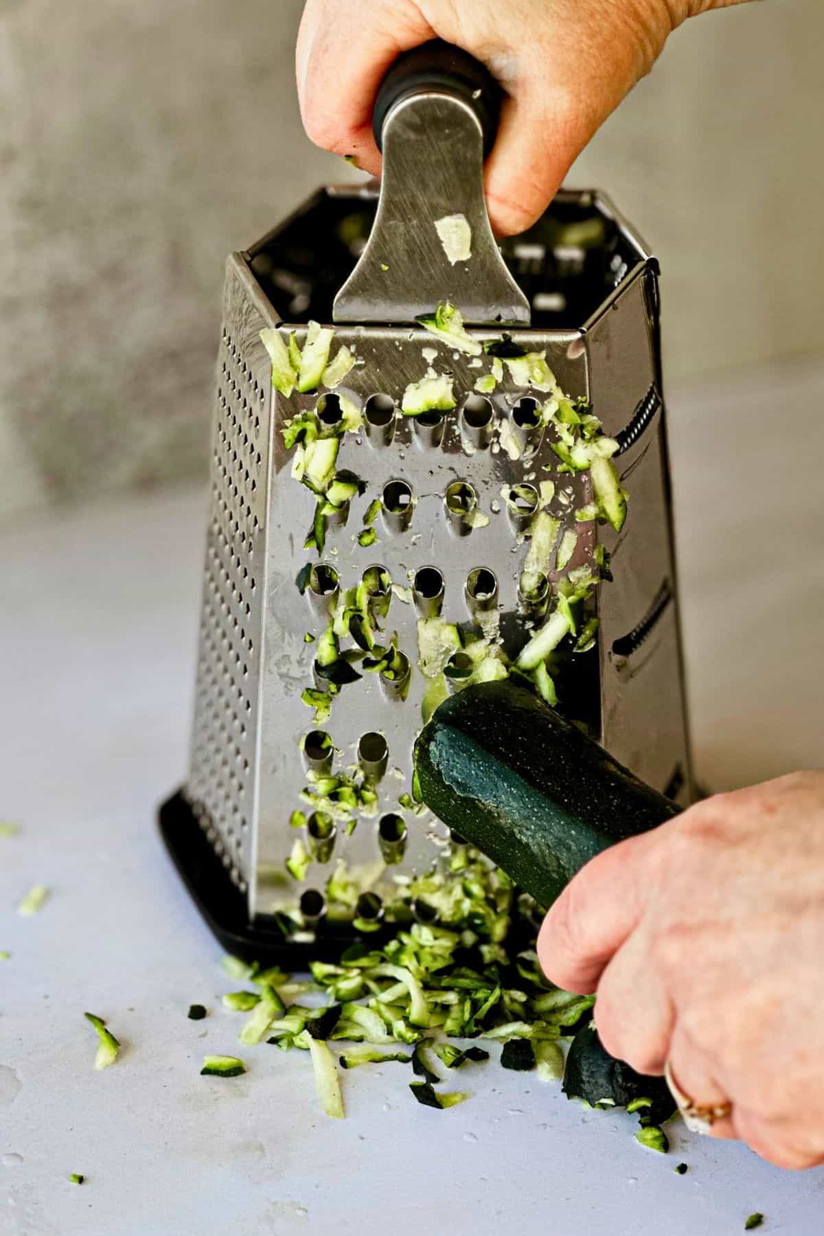 side view grating zucchini for savory vegan zucchini muffins