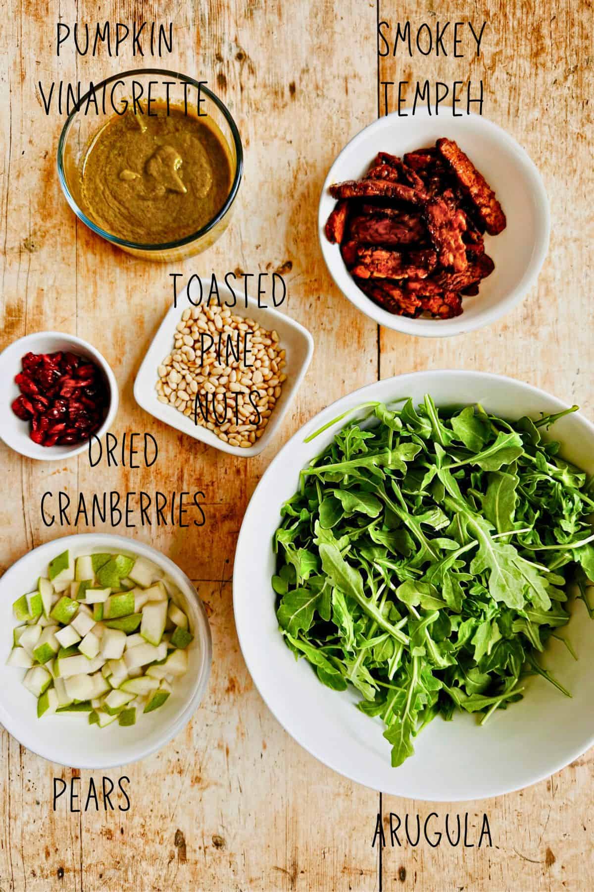 ingredients for arugula and pear salad with pumpkin vinaigrette in bowls