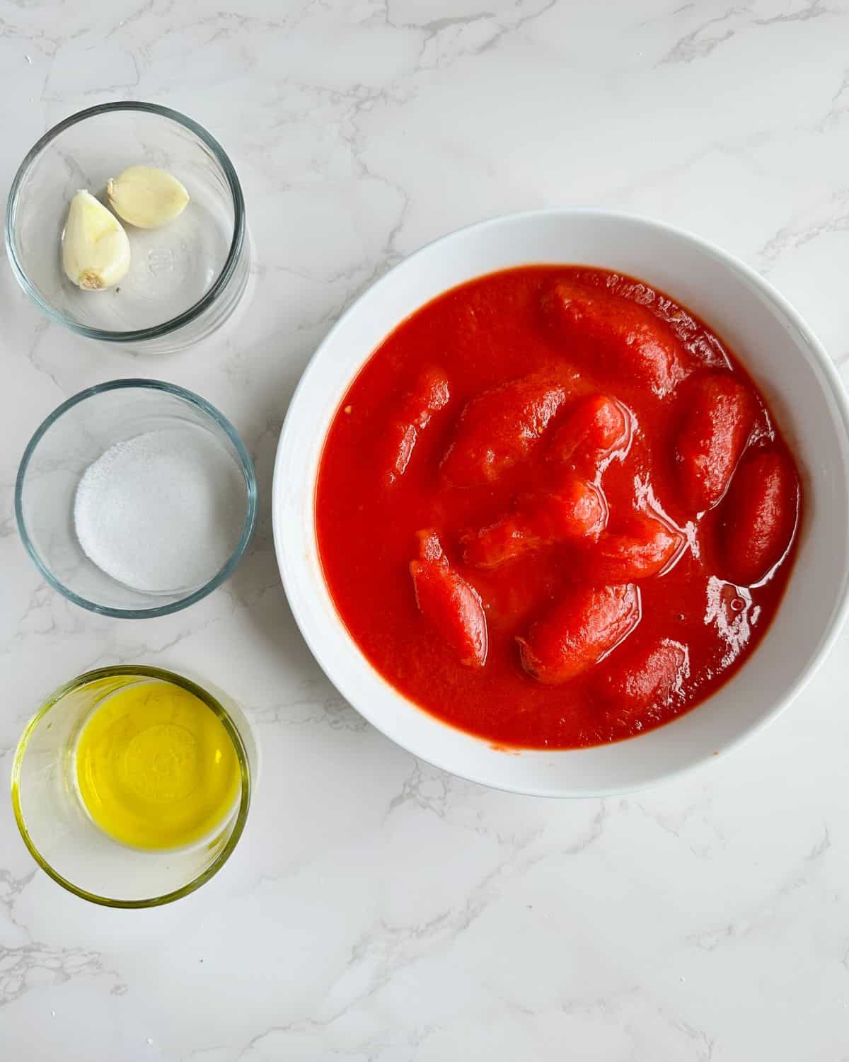 Ingredients for classic marinara sauce including olive oil, garlic, salt and tomatoes.