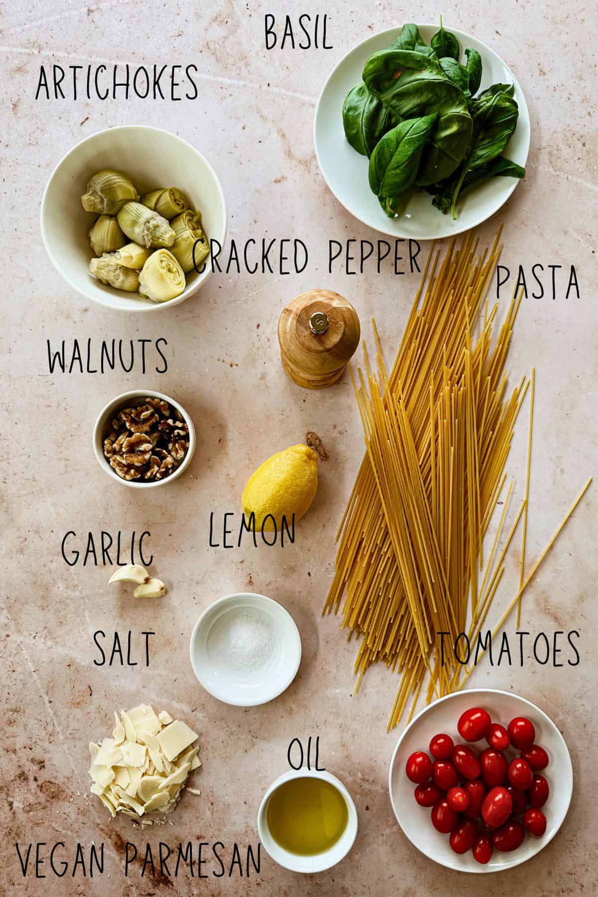 top view of ingredients for vegan lemon artichoke pesto pasta in bowls and on a table.