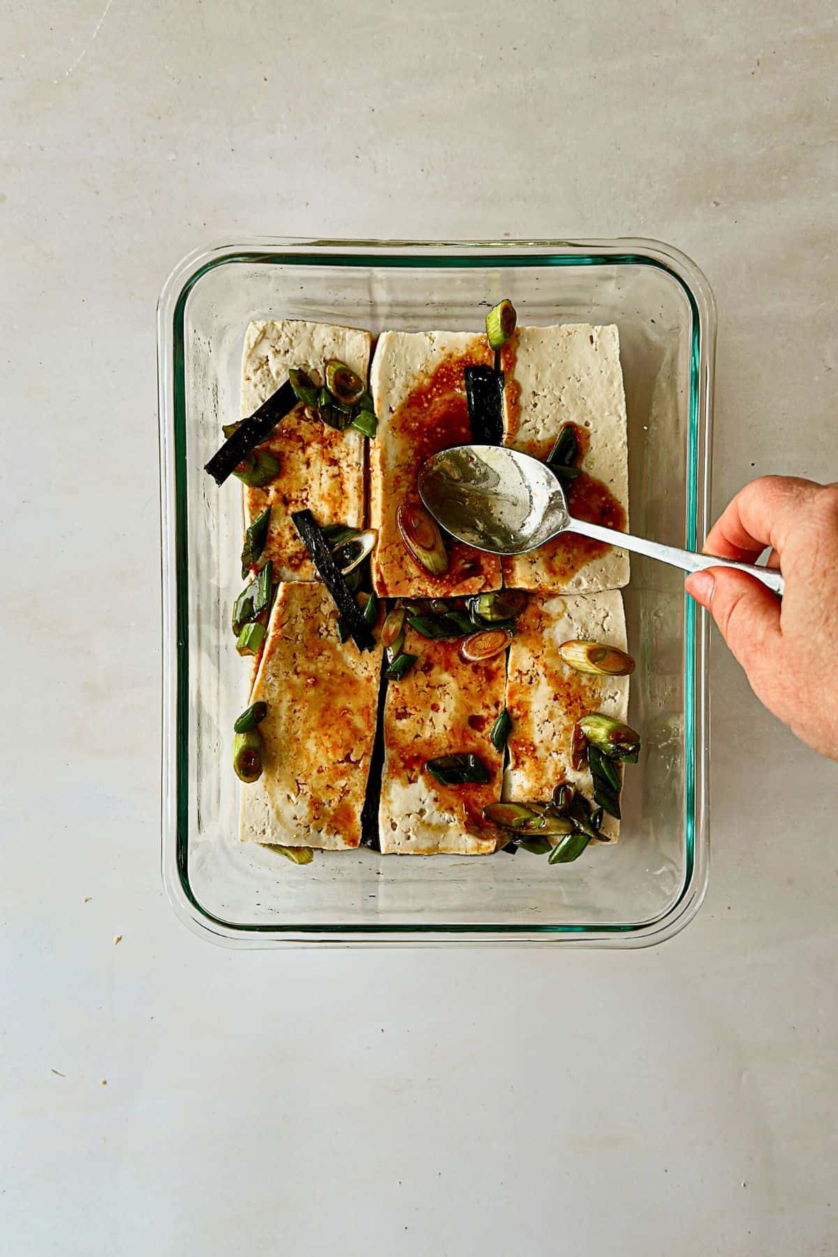 spooning marinade over the top of the tofu