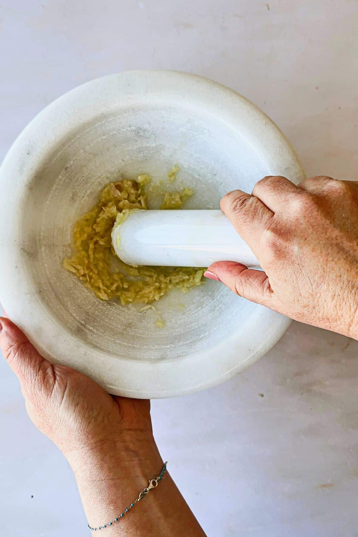 mashing garlic in mortar with pestle