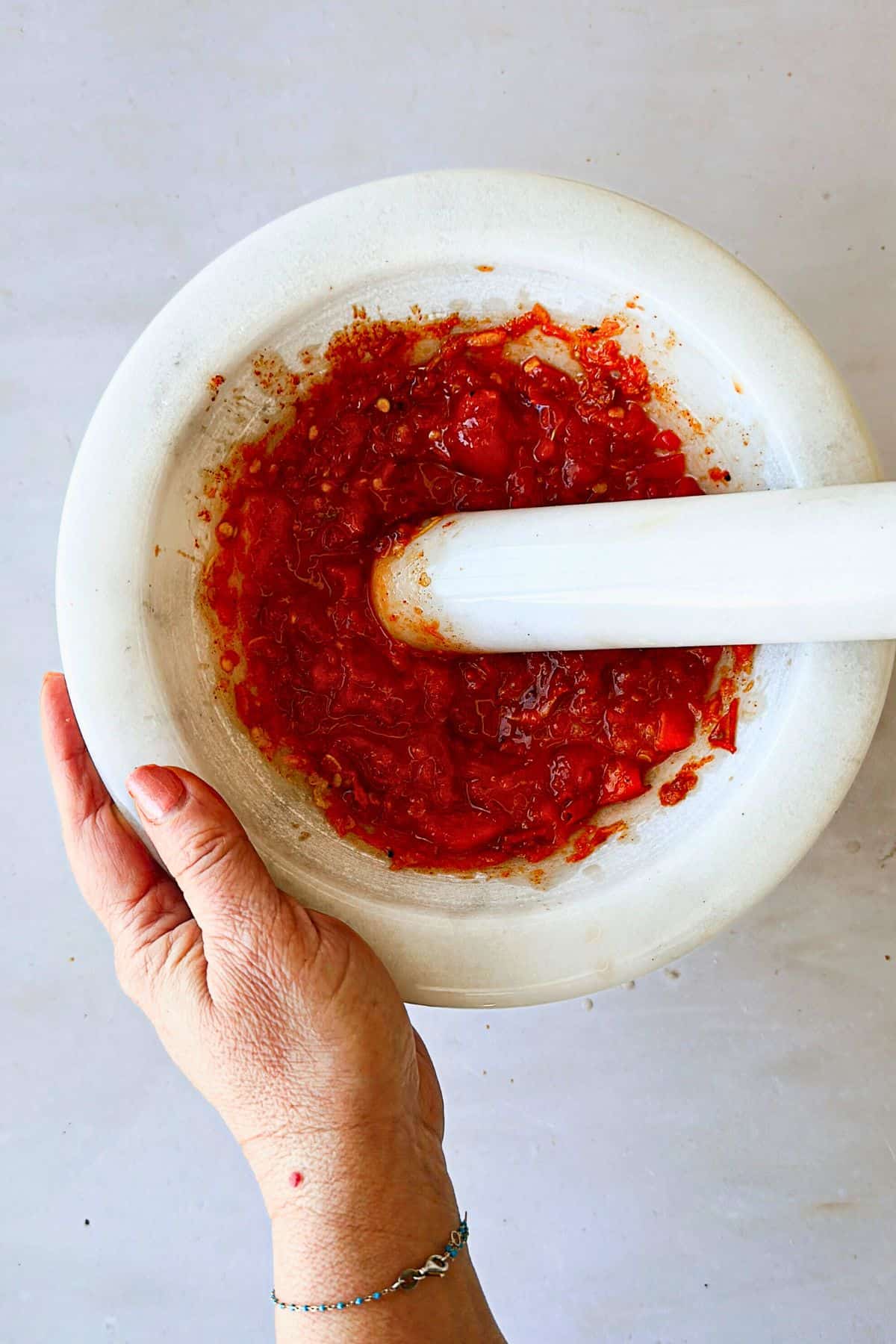 top view: mashing red peppers in a mortar