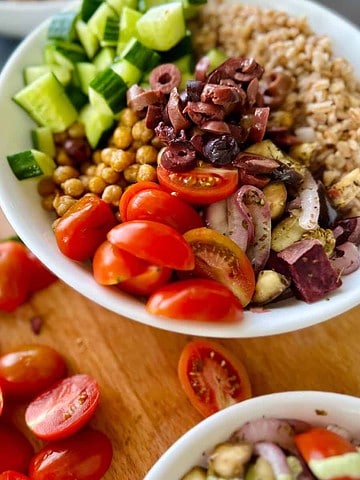 mediterranean grain bowl with chickpeas, farro, cucumbers, olives, tomatoes, and roasted onions and eggplant