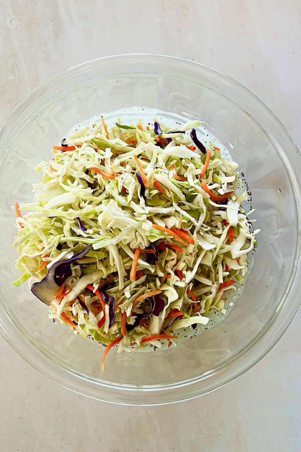 adding cabbage to vegan coleslaw in a bowl