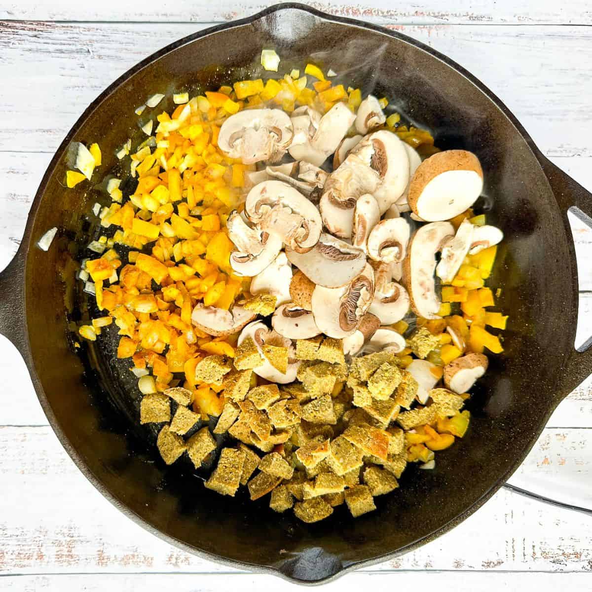 mushrooms and seitan added to tofu scramble in a cast iron pan