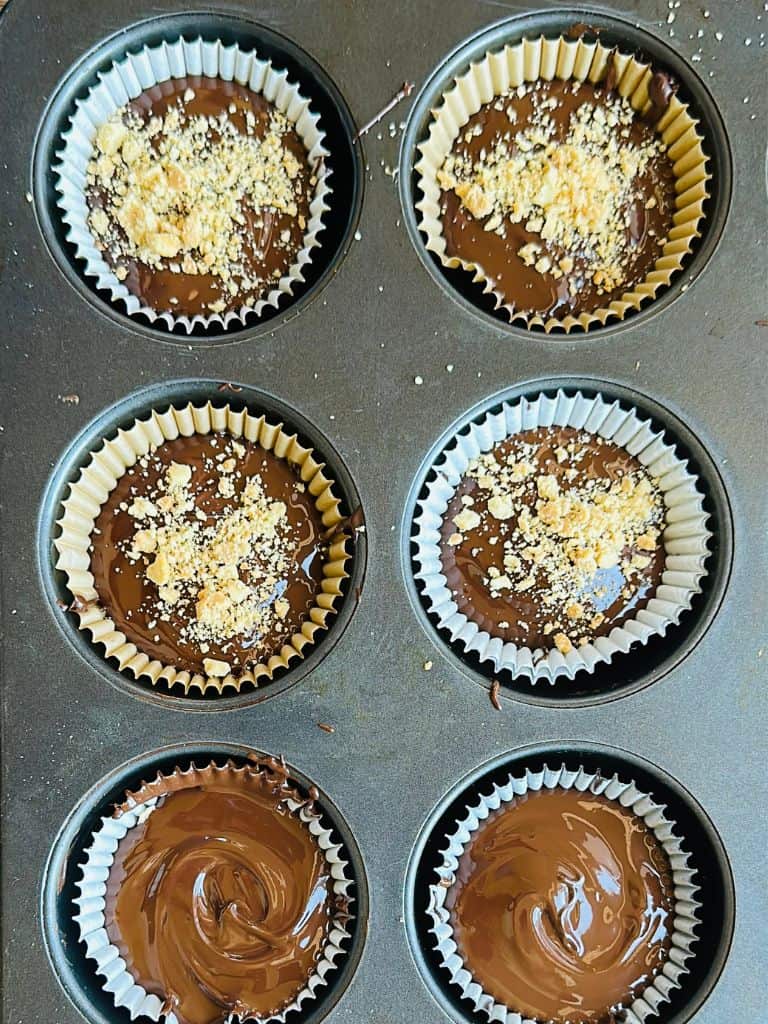 peanut butter cups with peanuts sprinkled on top in a muffin tray