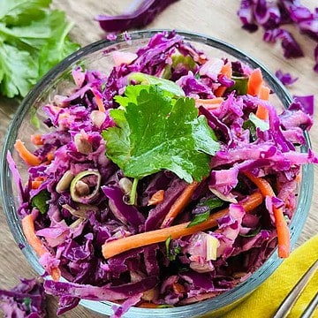 prepared purple cabbage slaw in a clear glass bowl ready to eat