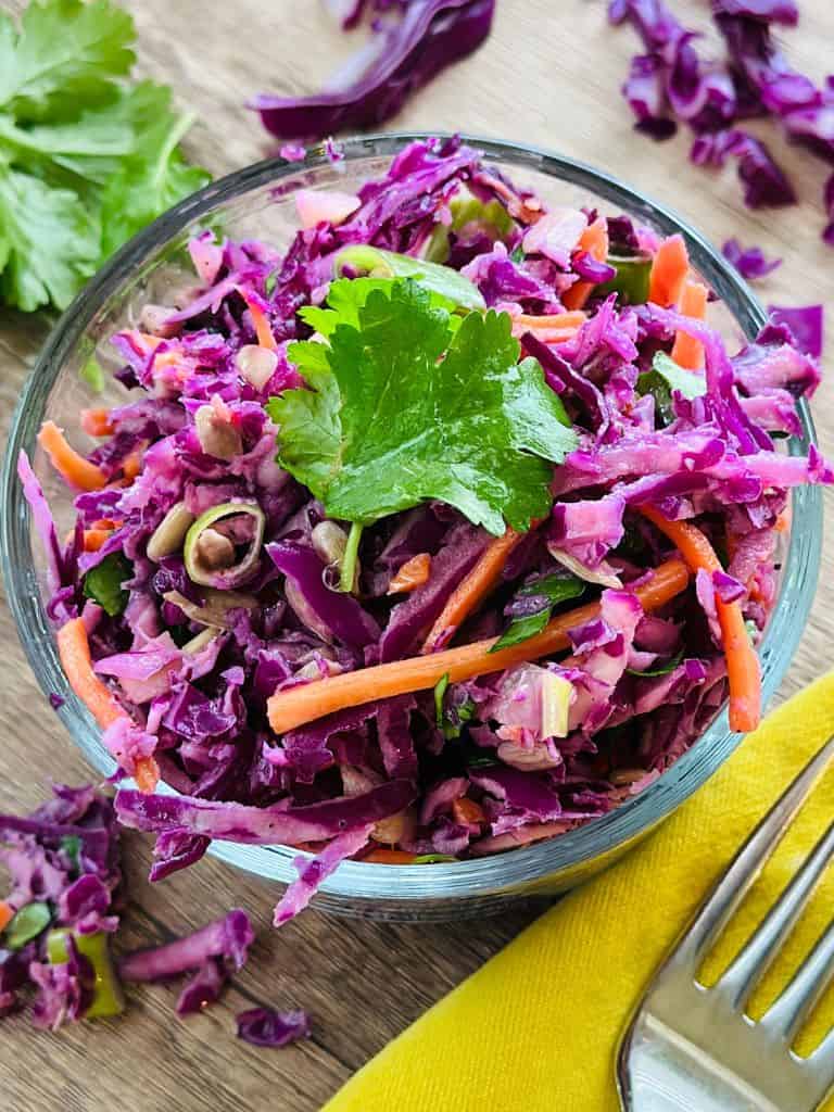 prepared purple cabbage slaw in a clear glass bowl ready to eat