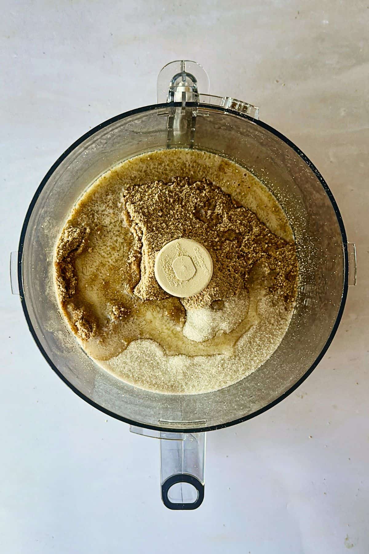 top view of food processor with the ingredients for the graham cracker crust mixture before mixing.