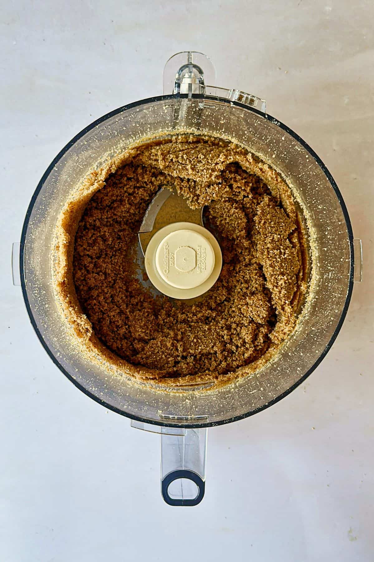 top view of graham cracker crust mixture in a food processor