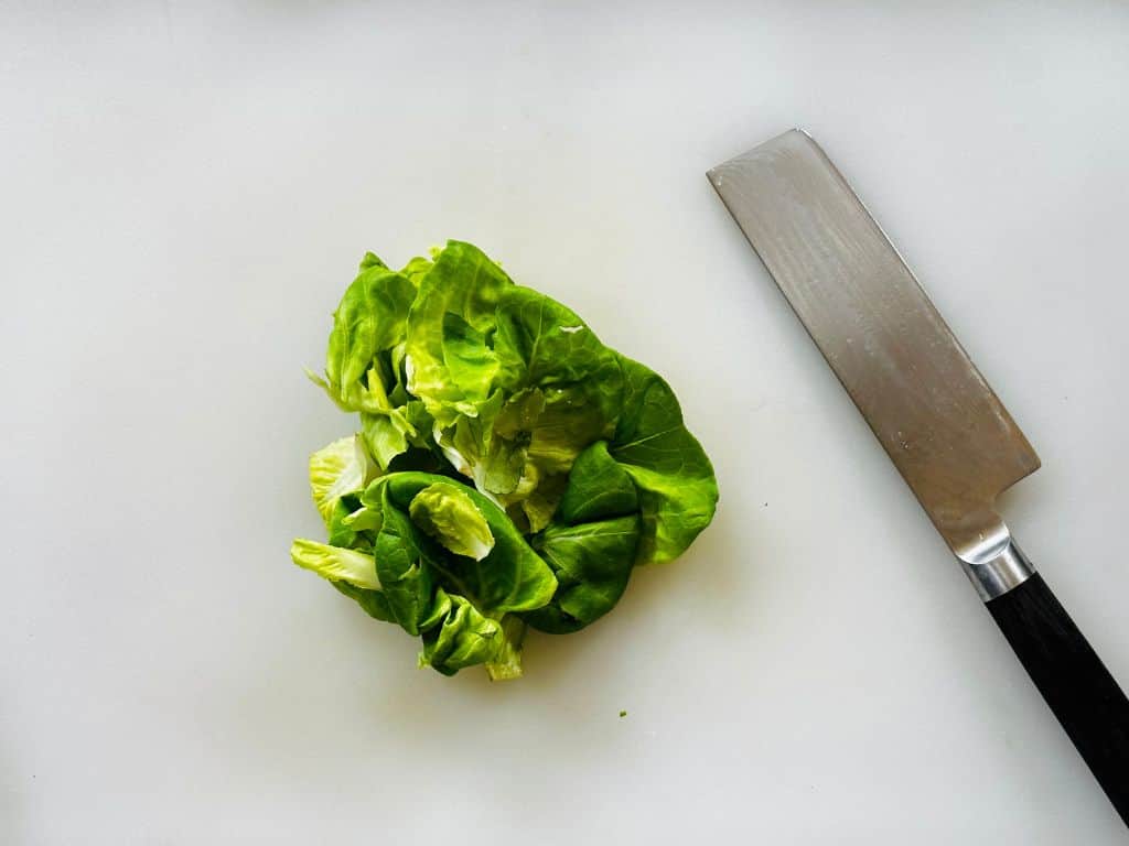 lettuce on a white cutting board with a knife placed next to it