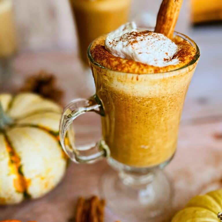 pumpkin spice steamer in a glass topped with whipped cream and cinnamon