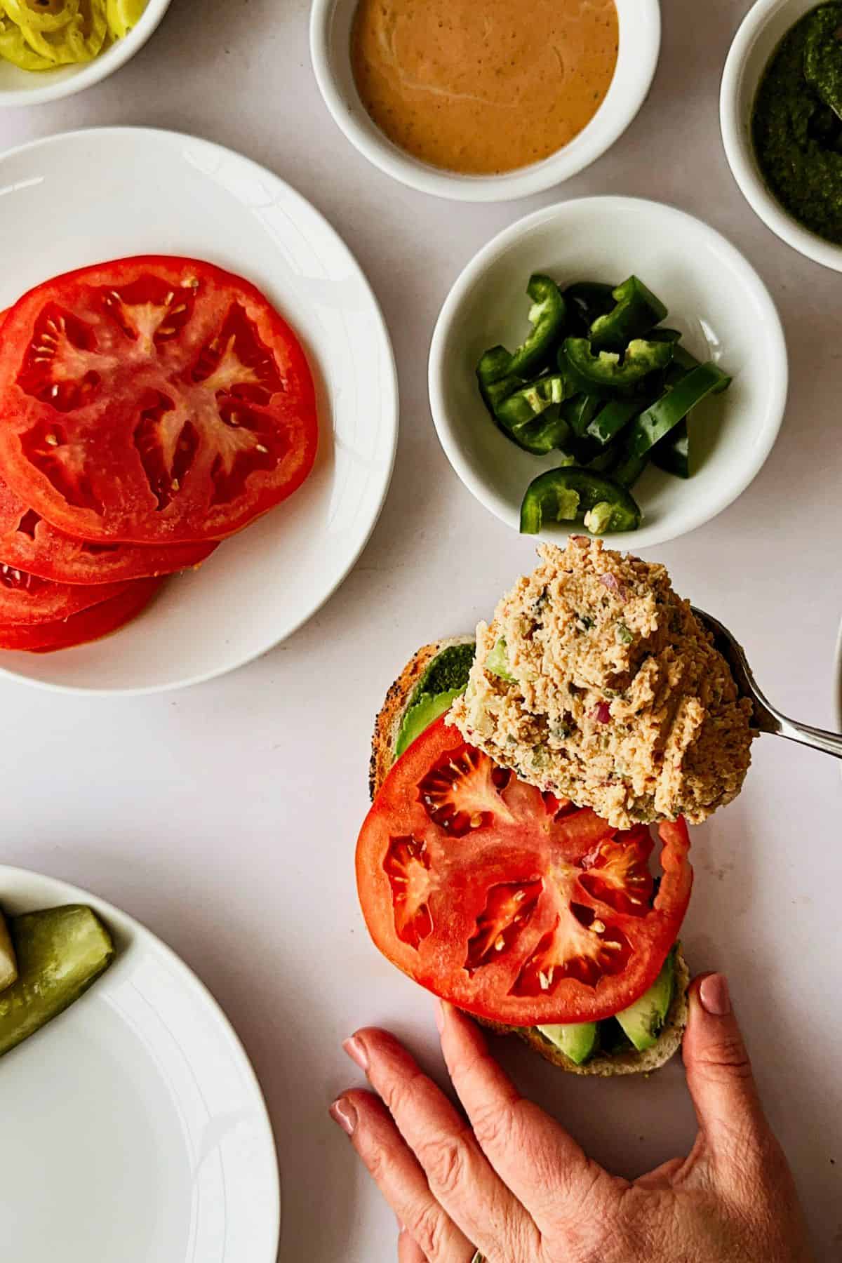 top view making a tunacado sandwich - spoon with scoop of vegan tuna going on sandwich bread