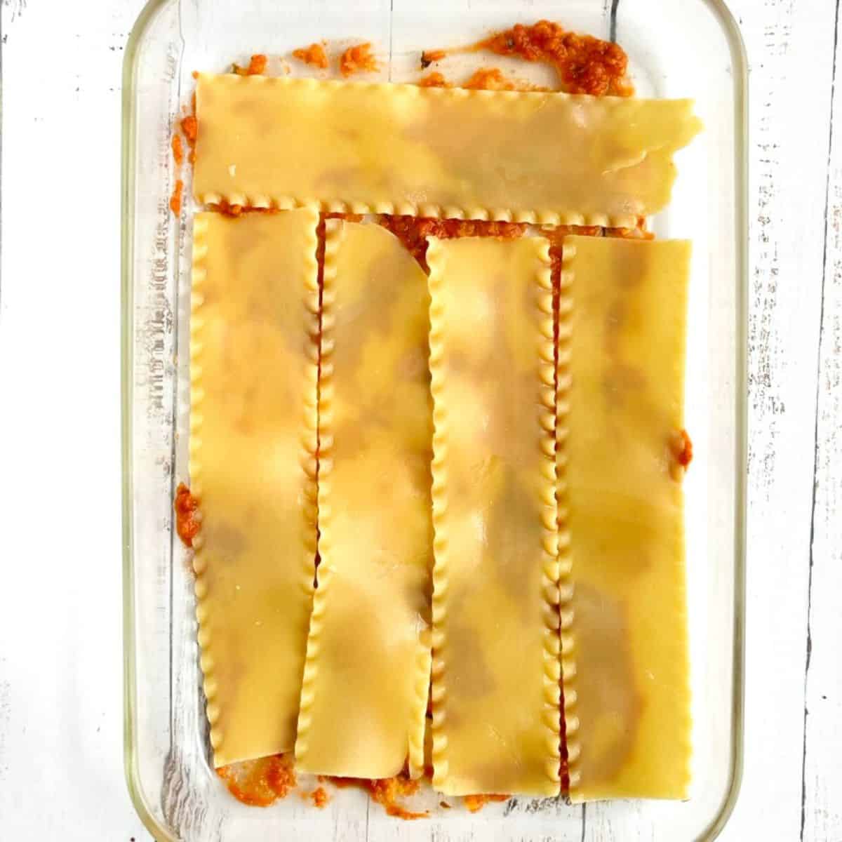 building the lasagna - step 2 placing lasagna noodles on top of marinara sauce