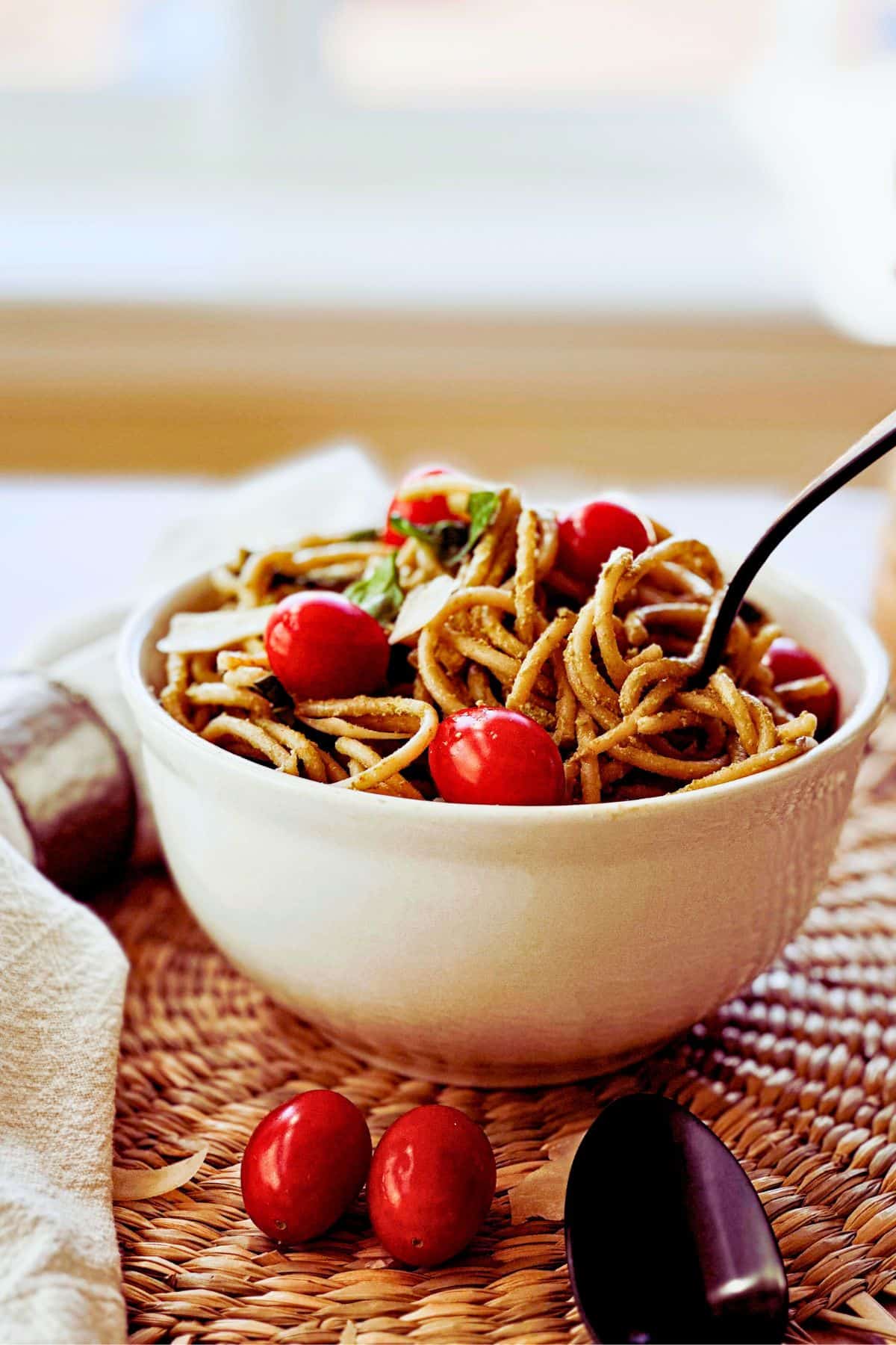 side view of bowl of Lemon Artichoke Pesto Pasta with a fork swirling the pasta.